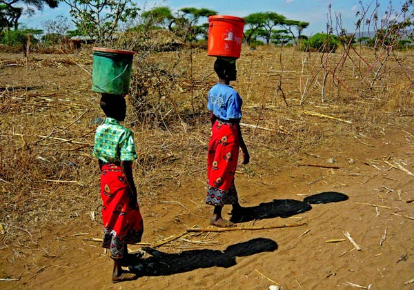 Villagers balance full water buckets on their heads, returning from their morning hike to a local spring.