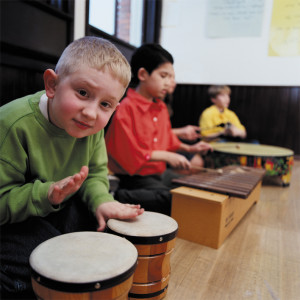Group of students (8-10) playing musical instruments in classroom
