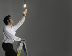Businessman changing light bulb, studio shot