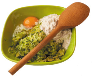 A bowl with flour, egg and grated zucchini for cooking pancakes