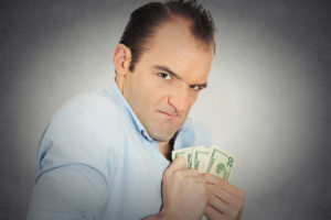 Closeup portrait greedy banker executive CEO boss, corporate employee funny looking man holding dollar banknotes scared to loose money, suspicious isolated grey background. Human face expression